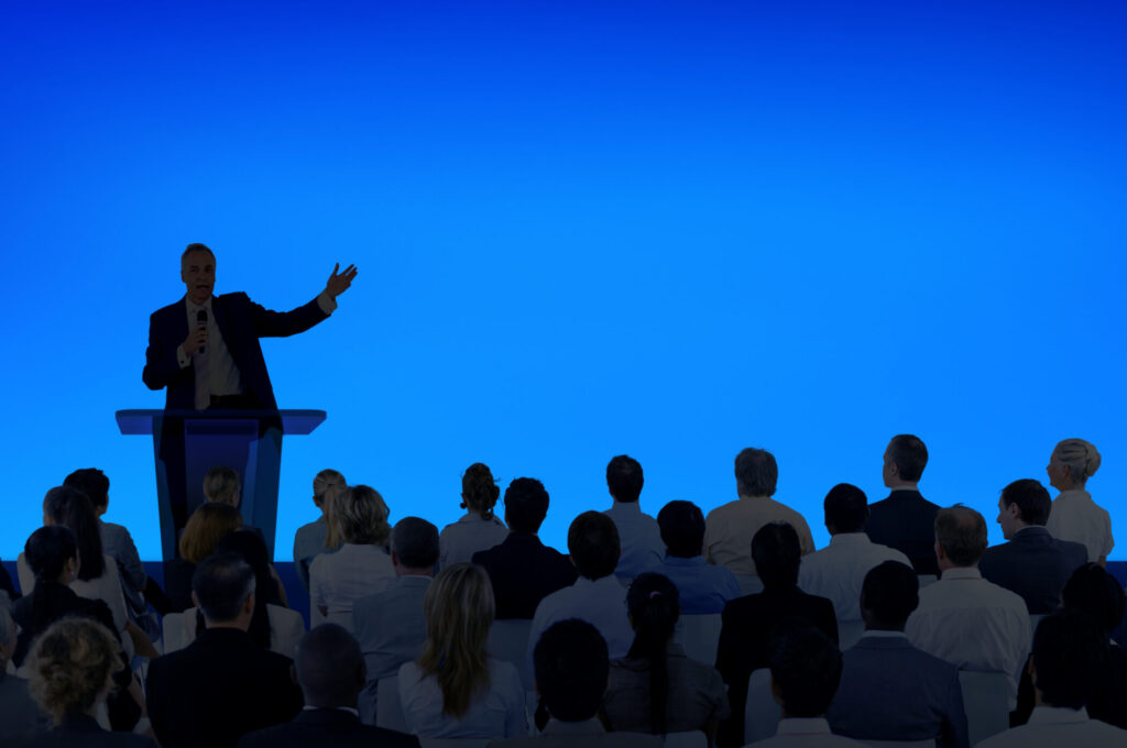 corporate businessman giving a presentation to a large audience